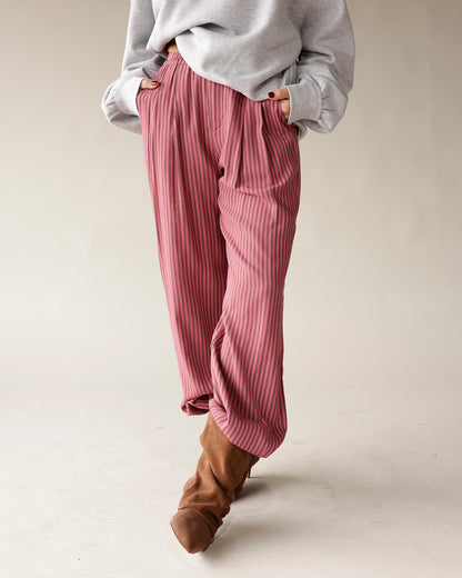 Pink striped wide-leg pleated trousers with elastic waist, styled with brown boots