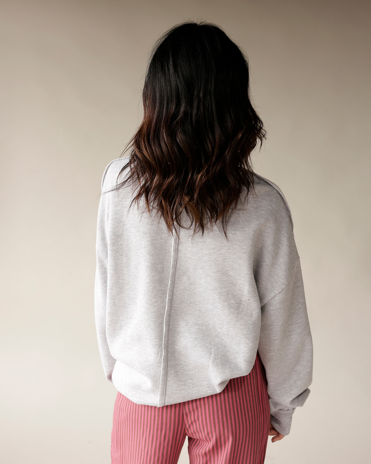 Women's oversized heather gray sweatshirt with center back seam, paired with pink striped pants