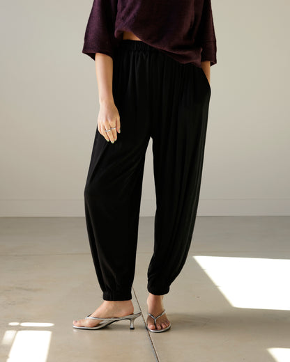 mimosa black balloon pants with an elastic waistband, relaxed draped silhouette and gathered ankle hems, styled with silver kitten heels.