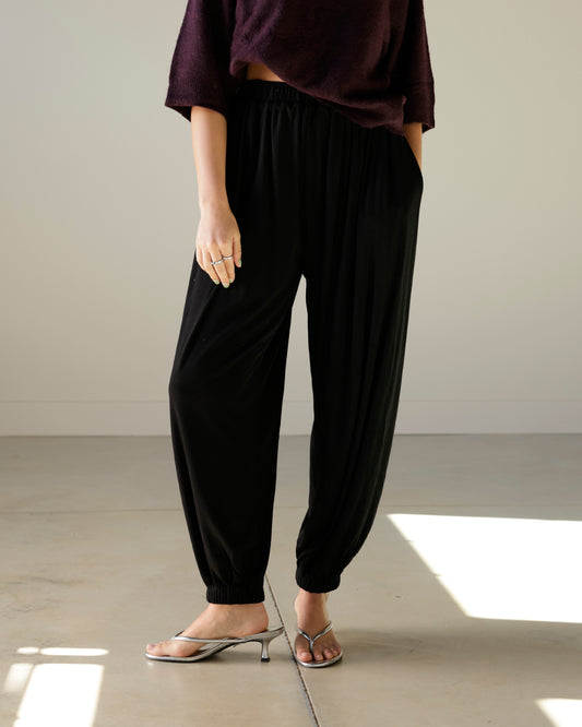 mimosa black balloon pants with an elastic waistband, relaxed draped silhouette and gathered ankle hems, styled with silver kitten heels.