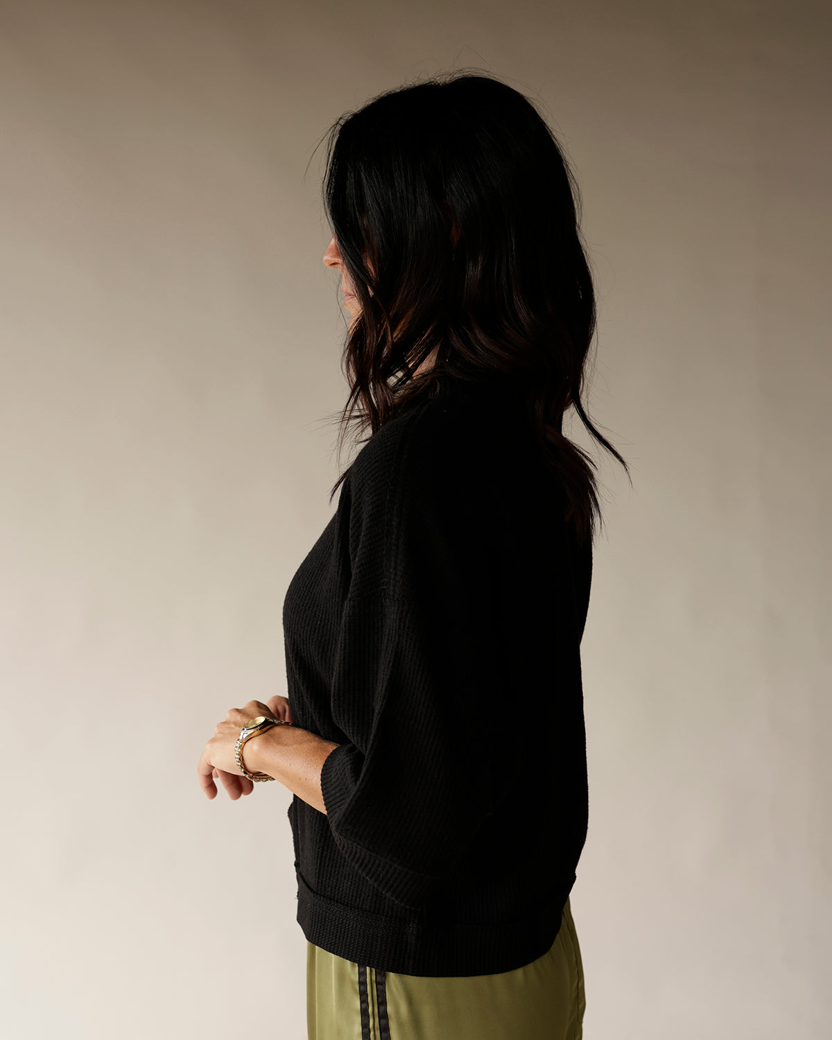 Women's black ribbed knit pullover sweater with 3/4 sleeves, side profile view