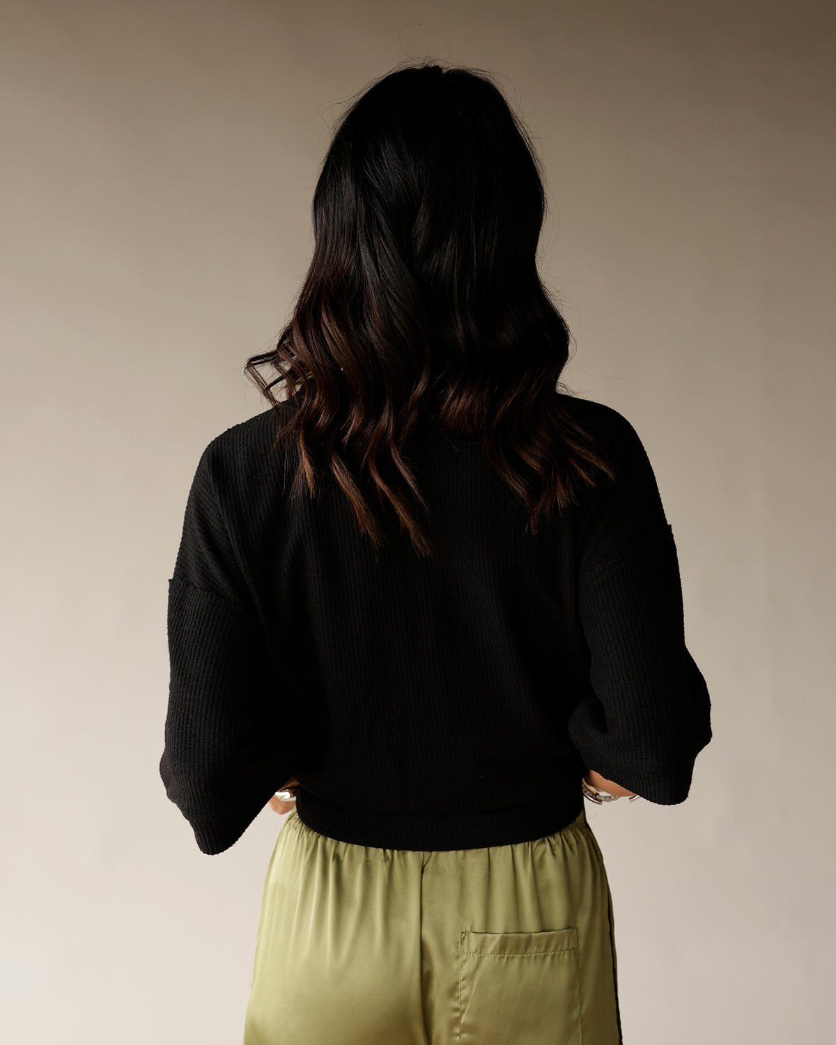 Women's black ribbed knit cropped sweater with long sleeves, back view
