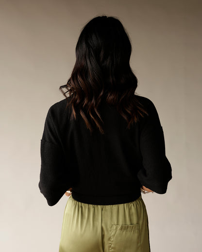 Women's black ribbed knit cropped sweater with long sleeves, back view