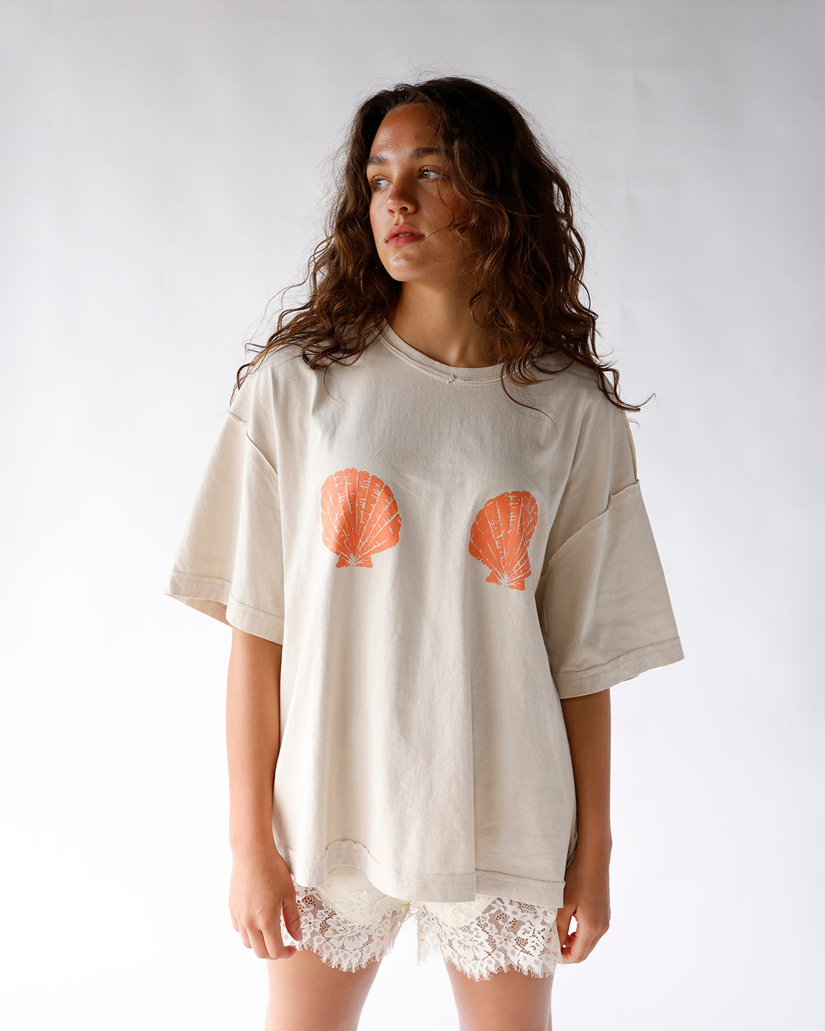 beige shirt with orange seashell graphics across chest seashell graphic tshirt