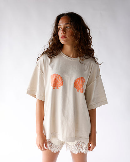 beige shirt with orange seashell graphics across chest seashell graphic tshirt
