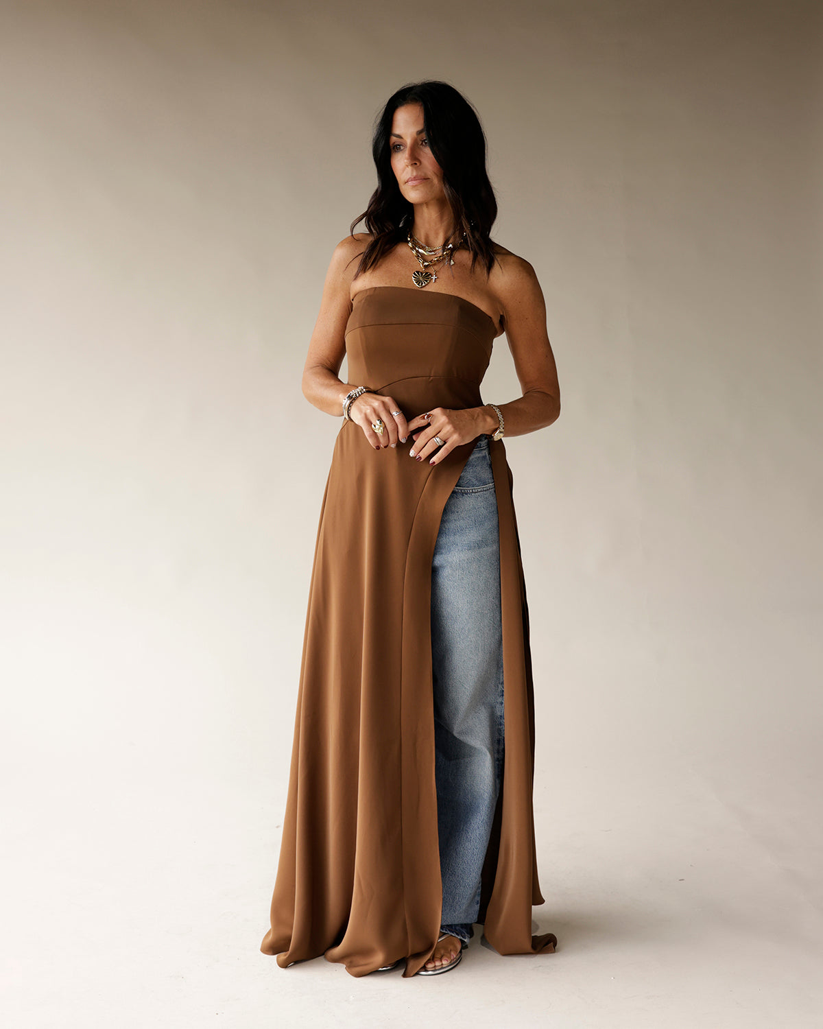 Brown strapless maxi tunic with high slit, styled over wide-leg jeans