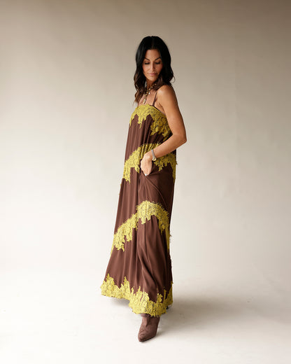 Brown maxi dress with yellow-green lace trim and thin straps on a woman