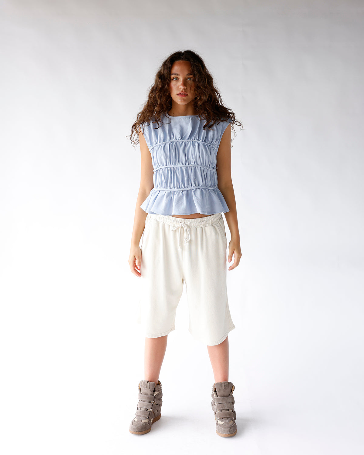 Light blue sleeveless ruched peplum top with tiered elastic banding detail