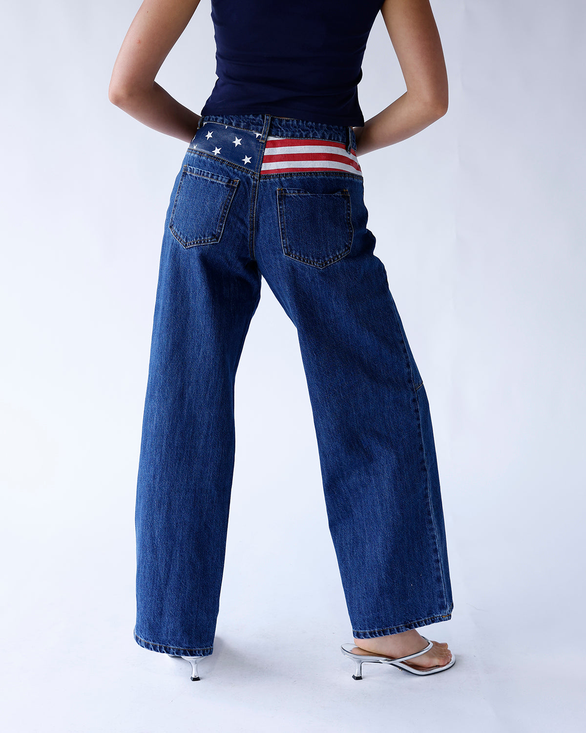 Dark denim wide leg jeans featuring an American flag detail above the back pockets. A bold, patriotic statement piece with a relaxed, trendy fit.