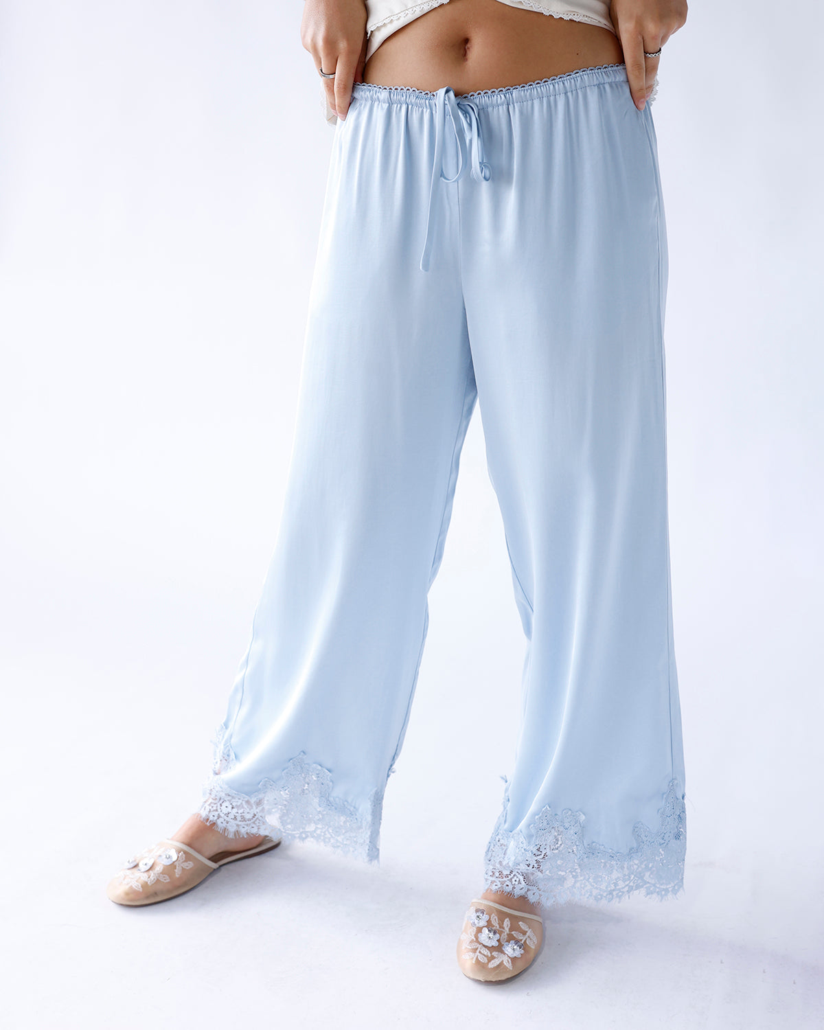 Light blue wide-leg satin pants with lace hem trim and drawstring waist