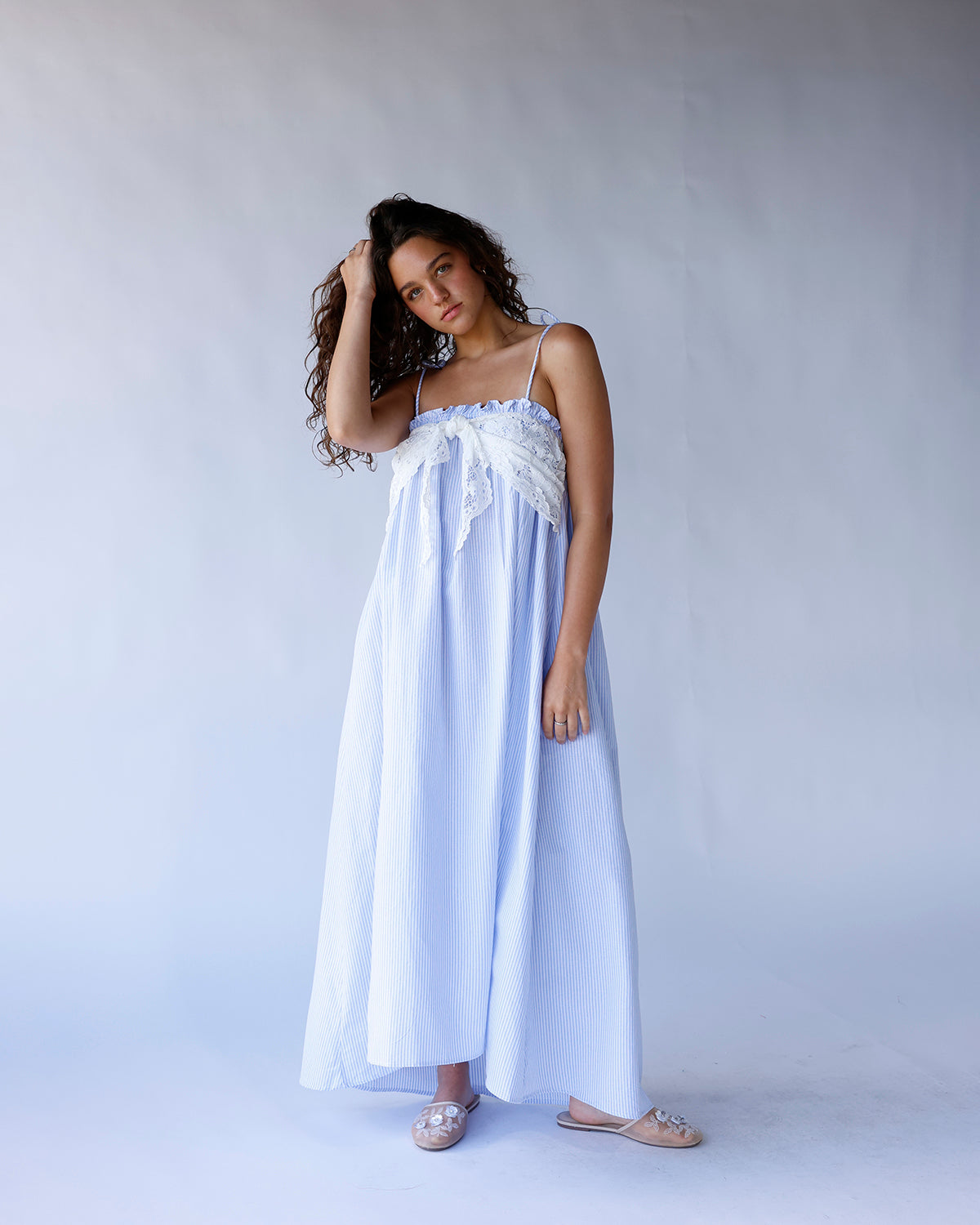 Blue and white striped long dress with spaghetti straps, elastic top, and lace front tie detail. A breezy, coastal-inspired summer dress perfect for vacations and warm days.