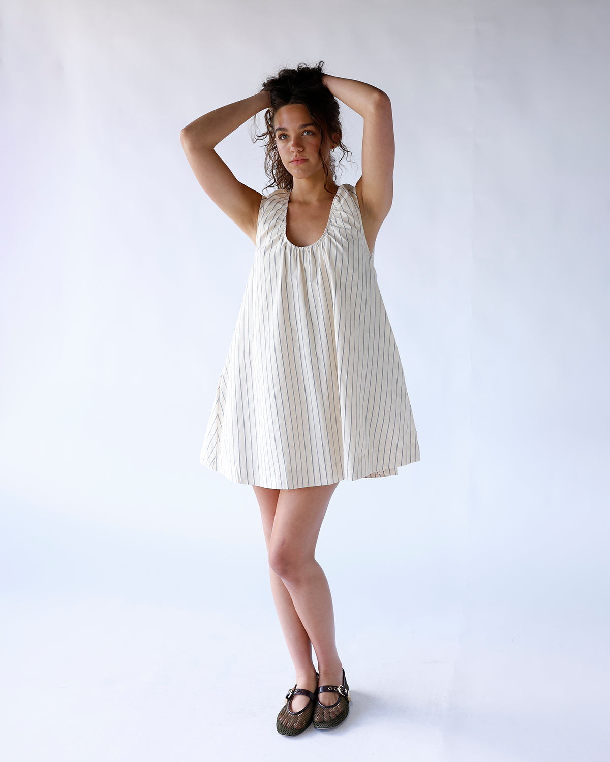 Cream striped sleeveless mini dress with deep scoop neck and flared skirt