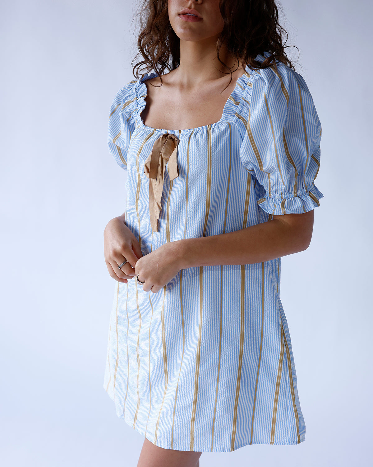 Blue striped seersucker mini dress with puff sleeves and tan tie neckline