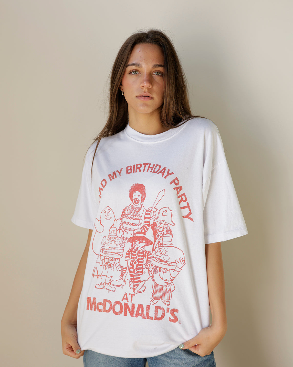white oversized graphic t-shirt featuring faded red vintage mcdonald's birthday party artwork, nostalgic characters and classic crew neckline.
