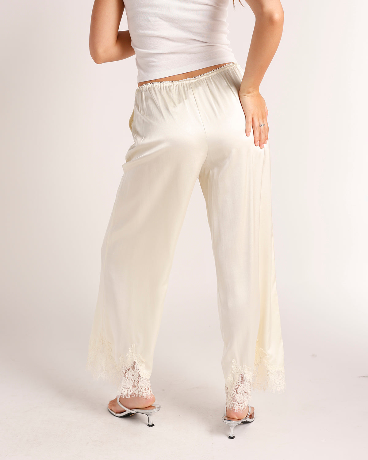 Cream satin wide-leg pants with lace trim hem and elastic waistband, back view