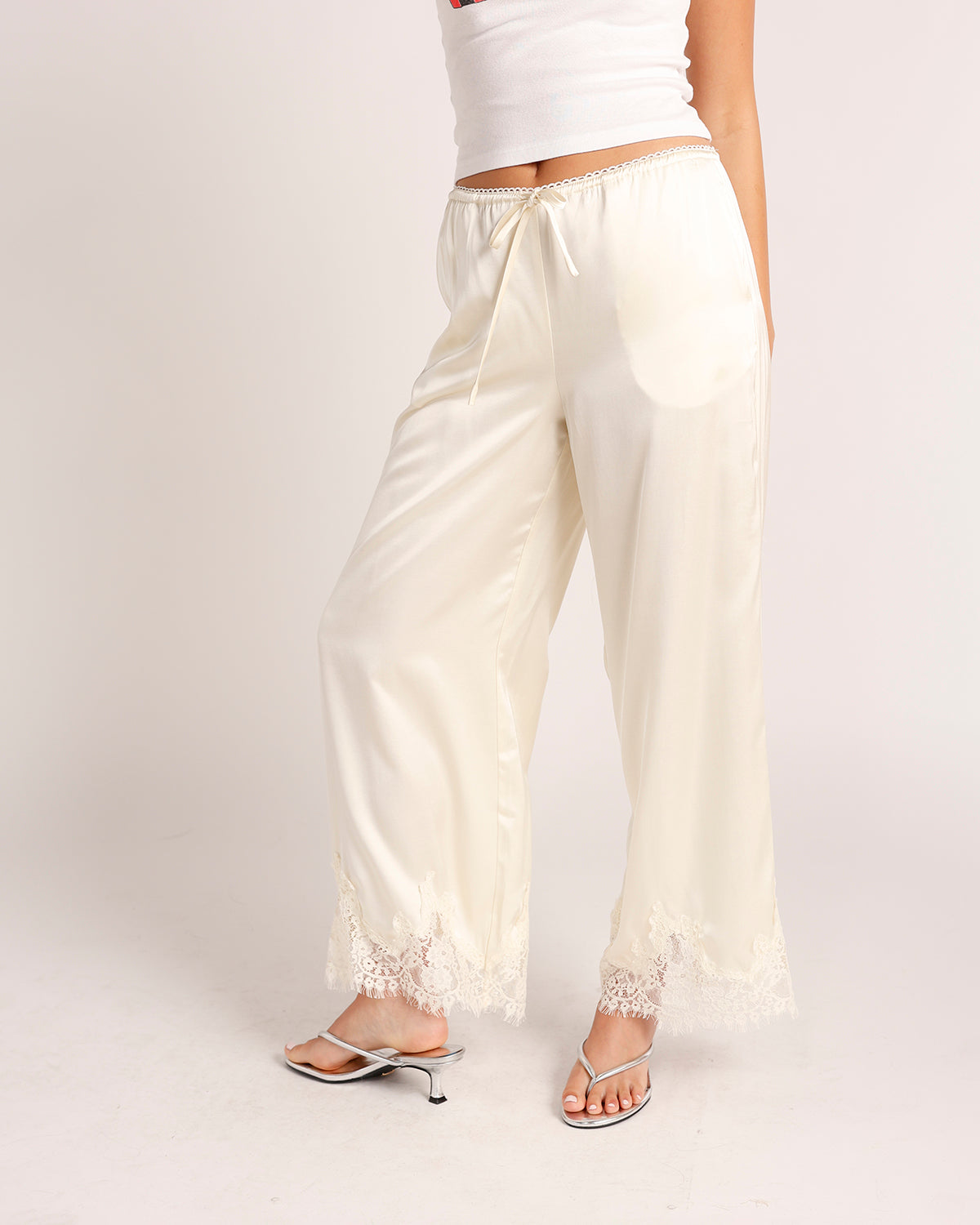 Cream satin wide-leg pants with lace trim hem and drawstring waist