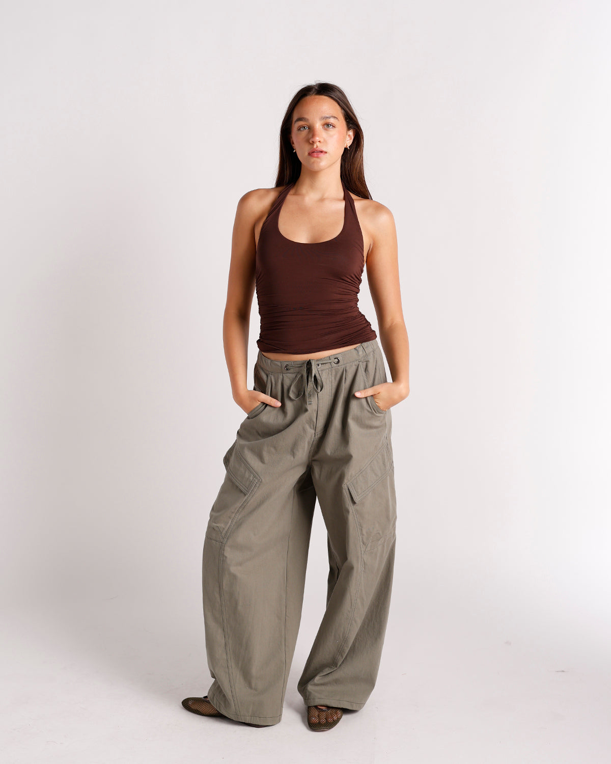 Wide-leg olive green cargo pants with pleats, side pockets, and drawstring waist.