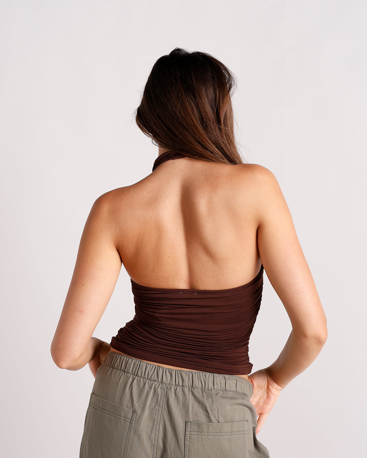 Dark brown ruched halter crop top with open back, paired with olive cargo pants.