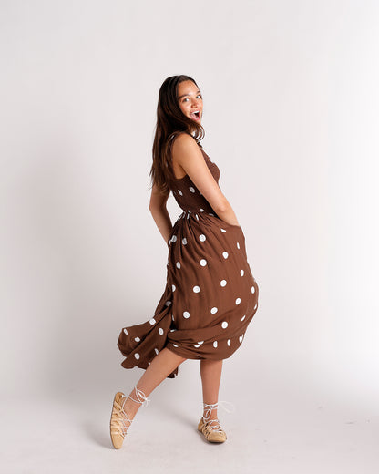 Camel suede lace-up flat sandals worn with a brown polka dot midi dress