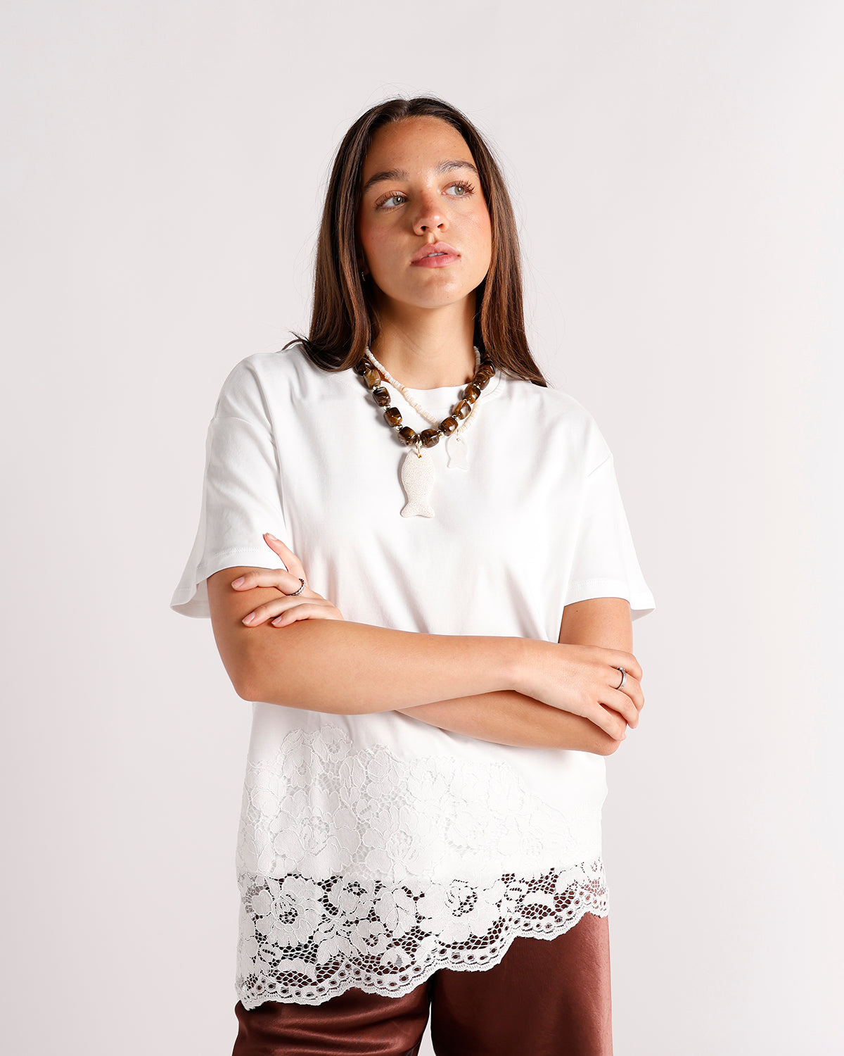 White short-sleeve top with lace hem panel, worn with brown beaded necklace and satin pants