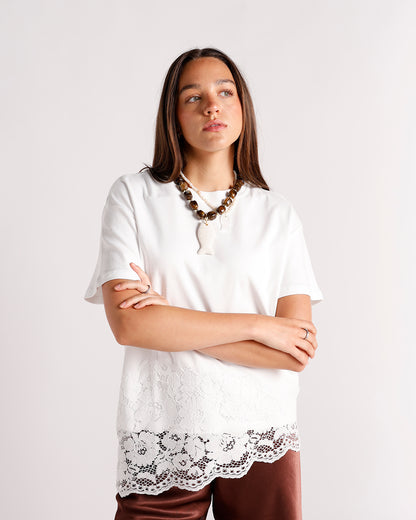 White short-sleeve top with lace hem panel, worn with brown beaded necklace and satin pants