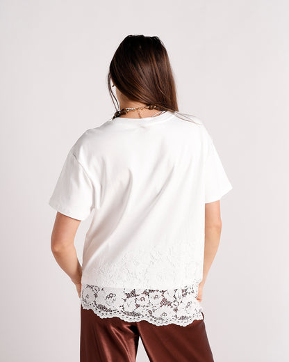 White short-sleeve top with lace hem detail, back view, worn with brown satin pants