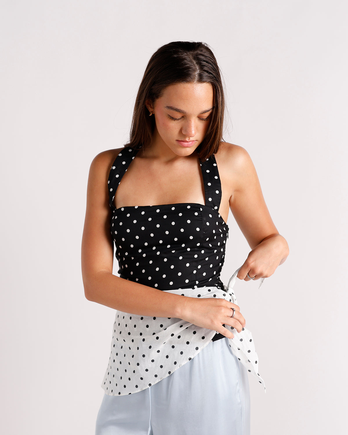 Black and white polka dot halter top with sheer tie detail, light blue pants