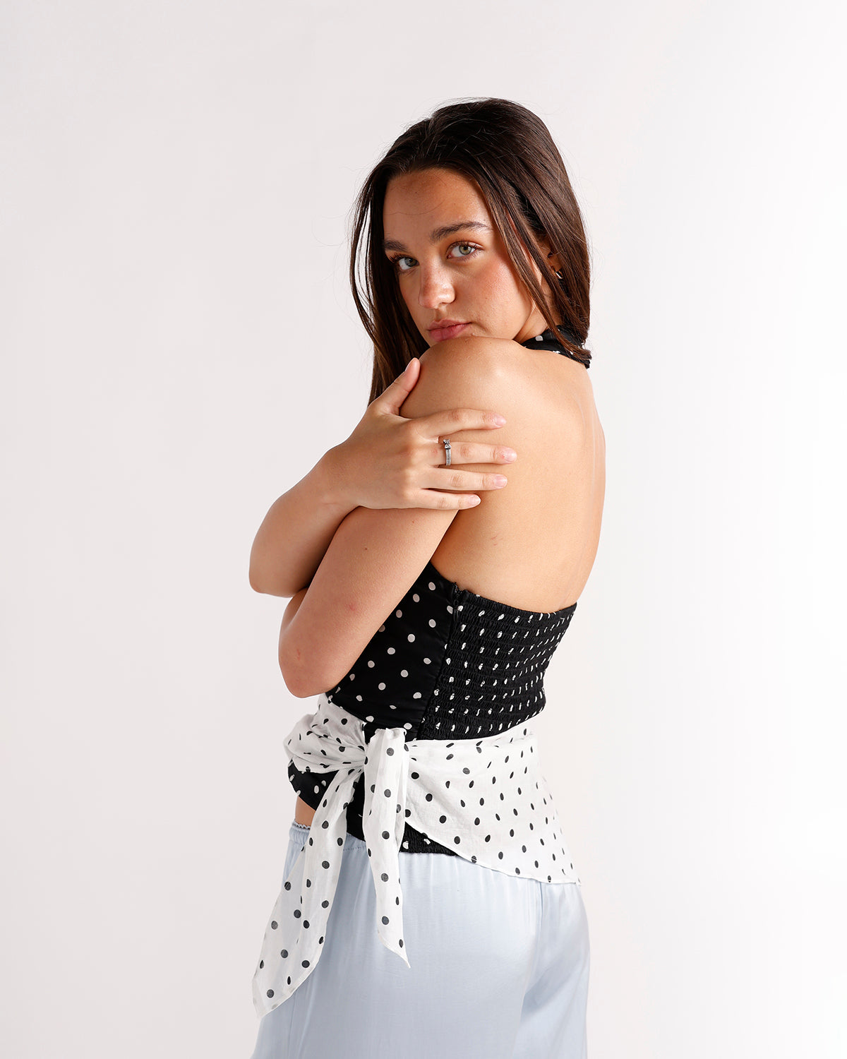 Black polka dot halter crop top with white tie back, worn with light blue skirt