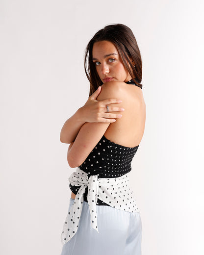 Black polka dot halter crop top with white tie back, worn with light blue skirt