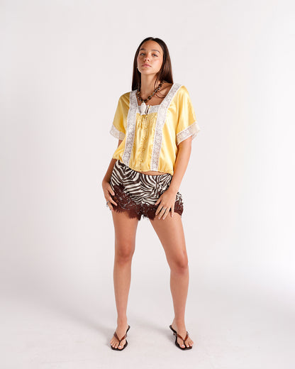 Yellow satin crop top with white lace trim, short sleeves, and button front detail