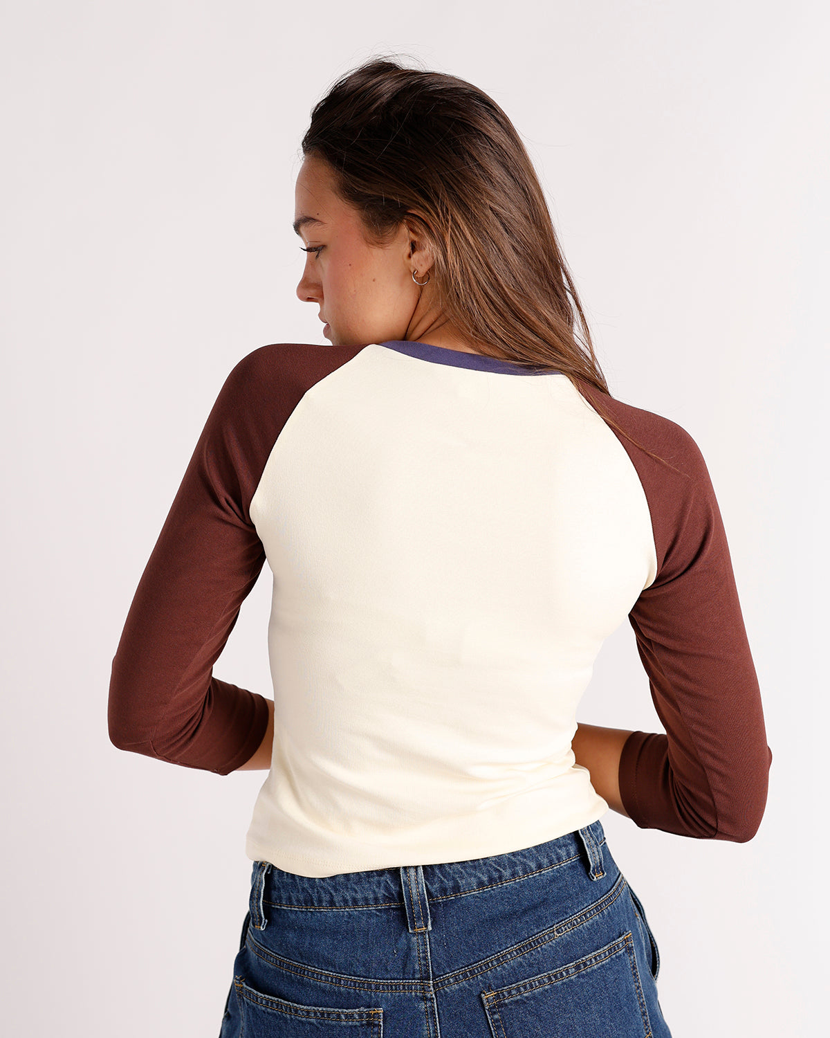 Back view of cream and brown raglan top with blue neckline trim, worn with jeans.
