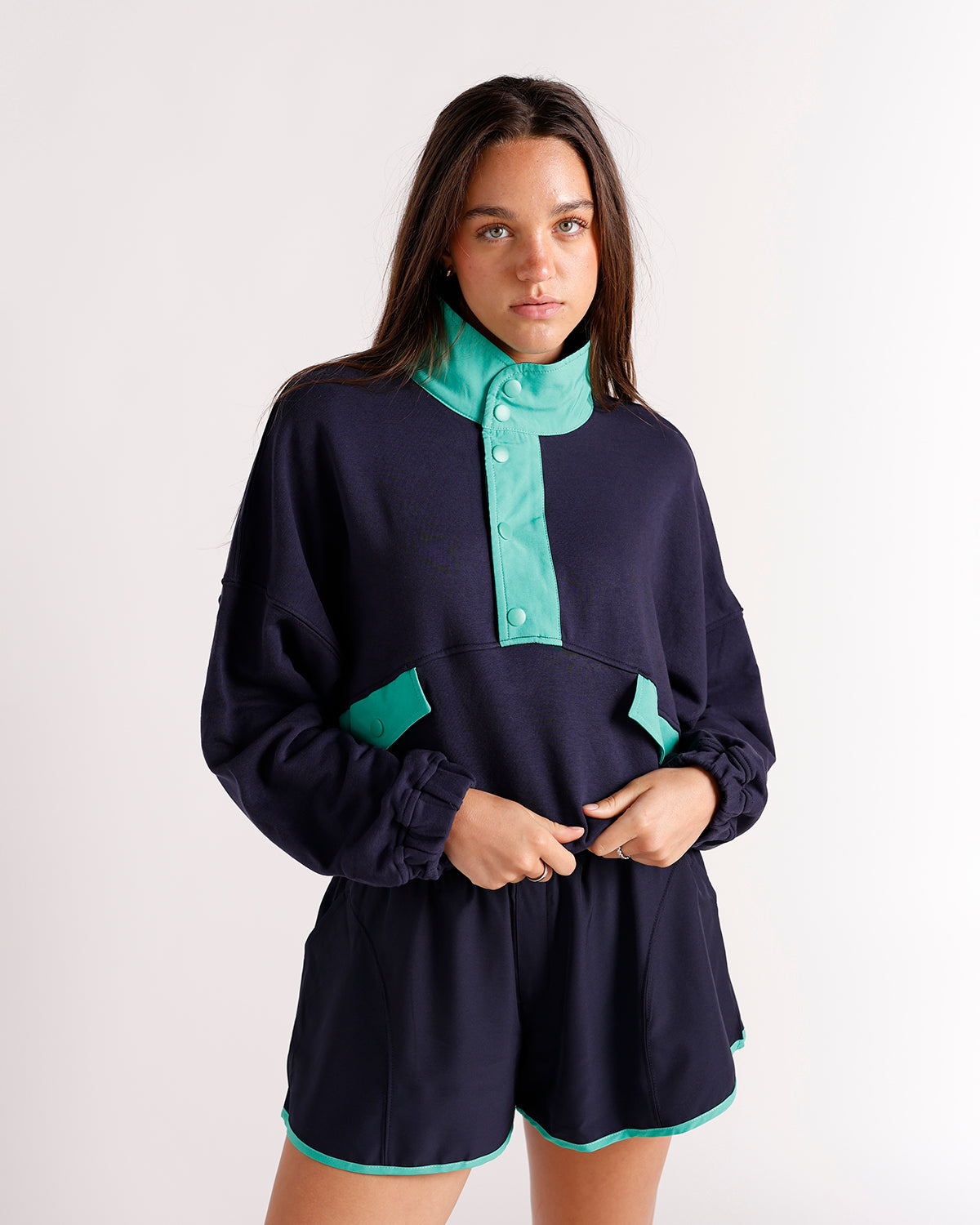 Navy blue snap-neck pullover sweatshirt with teal contrast collar and pocket trim