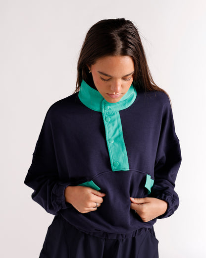 Navy blue pullover sweatshirt with teal snap-button collar and kangaroo pocket