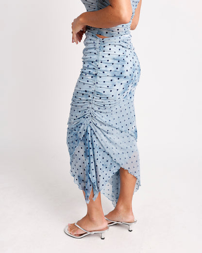 Light blue polka dot ruched midi skirt with asymmetric hem, worn with silver heels