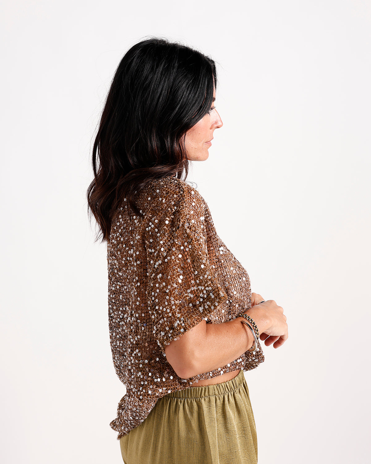 Bronze sequin short-sleeve crop top paired with olive green skirt, side view.