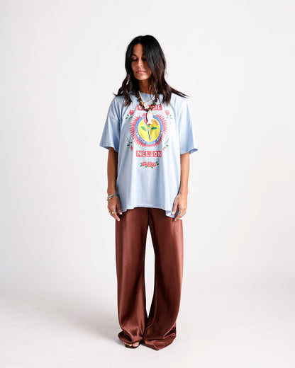 Oversized light blue graphic tee with brown wide-leg satin pants and beaded necklace