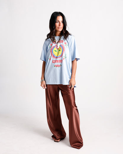 Oversized light blue graphic tee with rose print paired with wide-leg satin brown pants