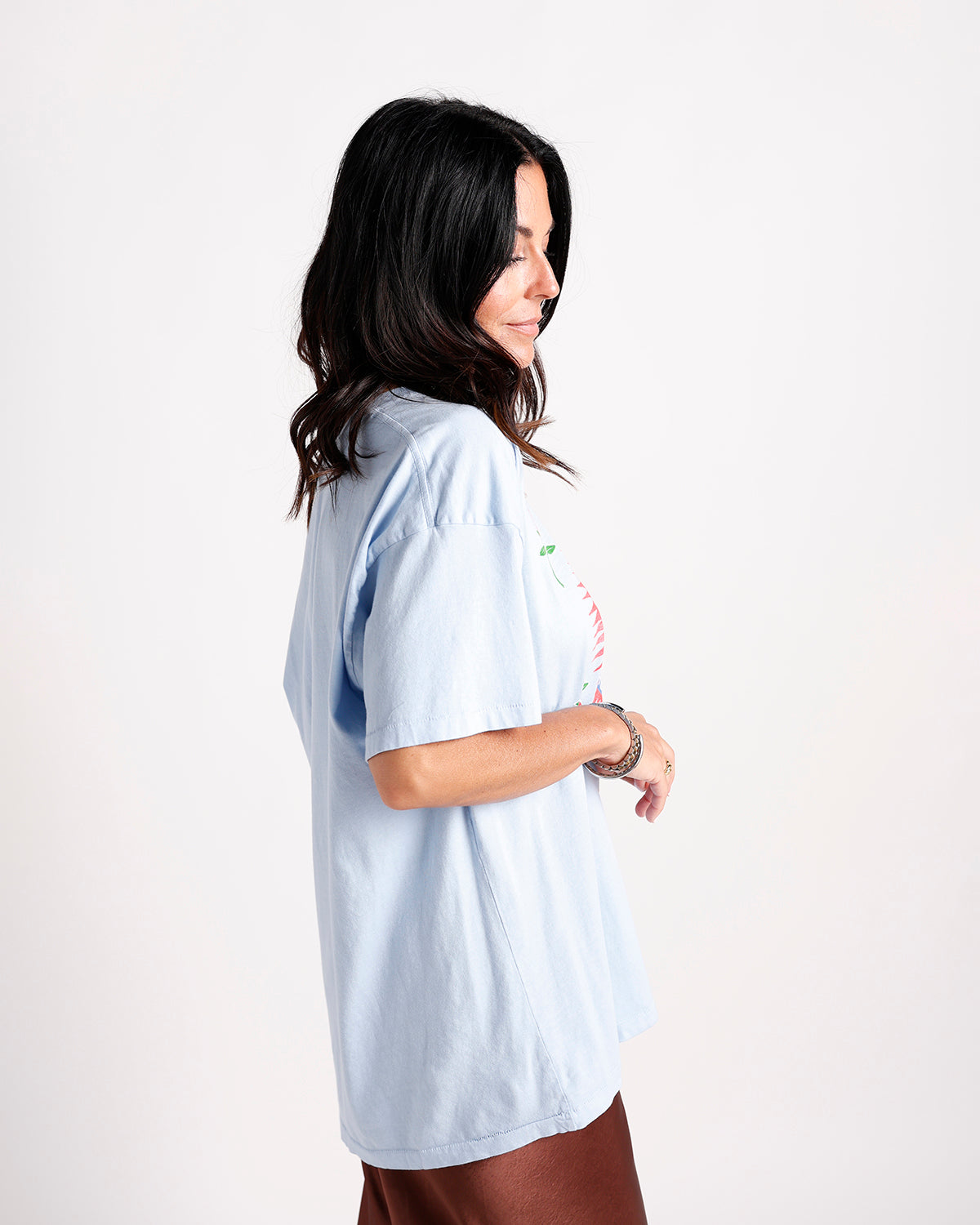 Woman wearing oversized light blue graphic tee with floral print, side view