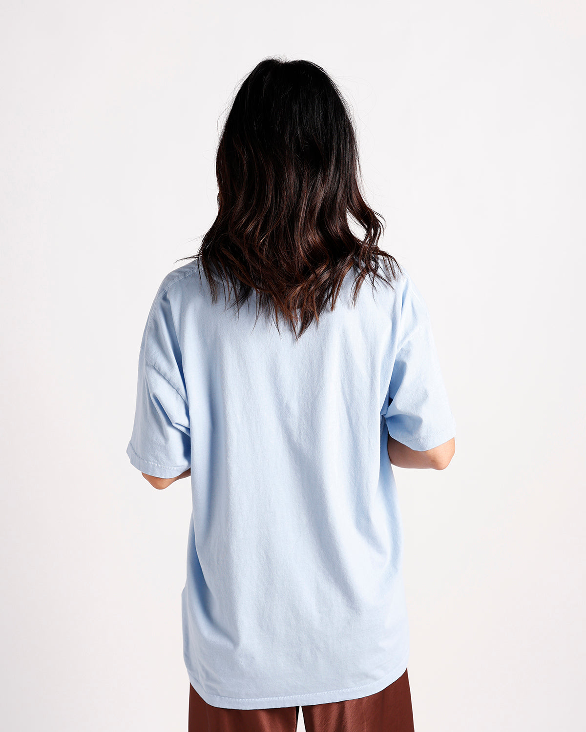 Back view of oversized light blue short sleeve tee with brown pants