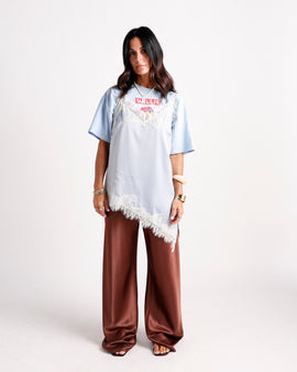 Light blue lace-trim slip top layered over graphic tee with wide-leg satin pants