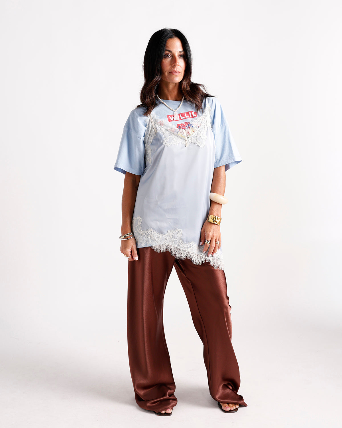 Light blue lace-trim slip top layered over graphic tee with brown satin wide-leg pants