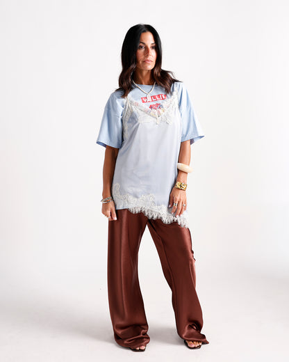 Light blue lace-trim slip top layered over graphic tee with brown satin wide-leg pants