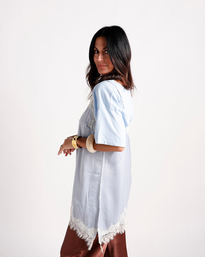 Light blue satin short-sleeve top with white lace trim hem, side view
