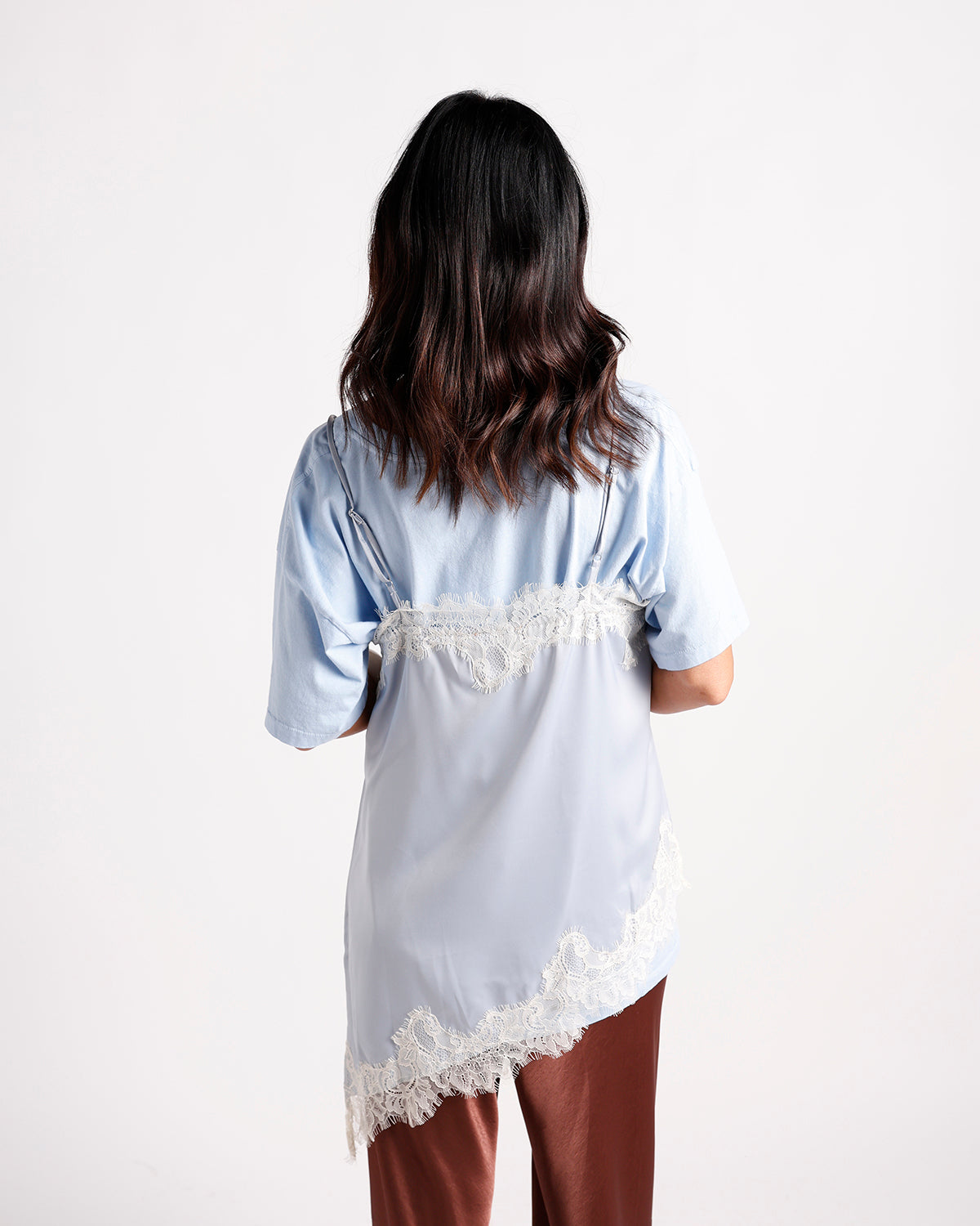 Light blue satin top with white lace trim, back view, worn with rust pants