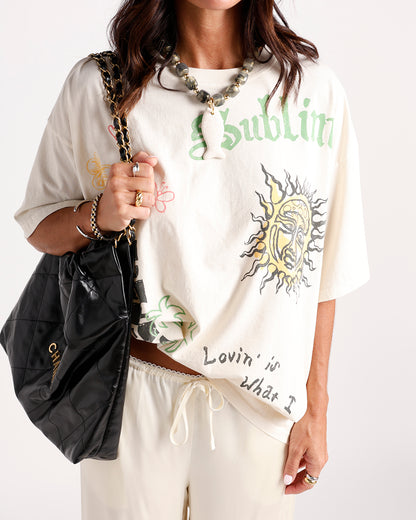 Oversized cream graphic tee with sun print and retro band-style artwork