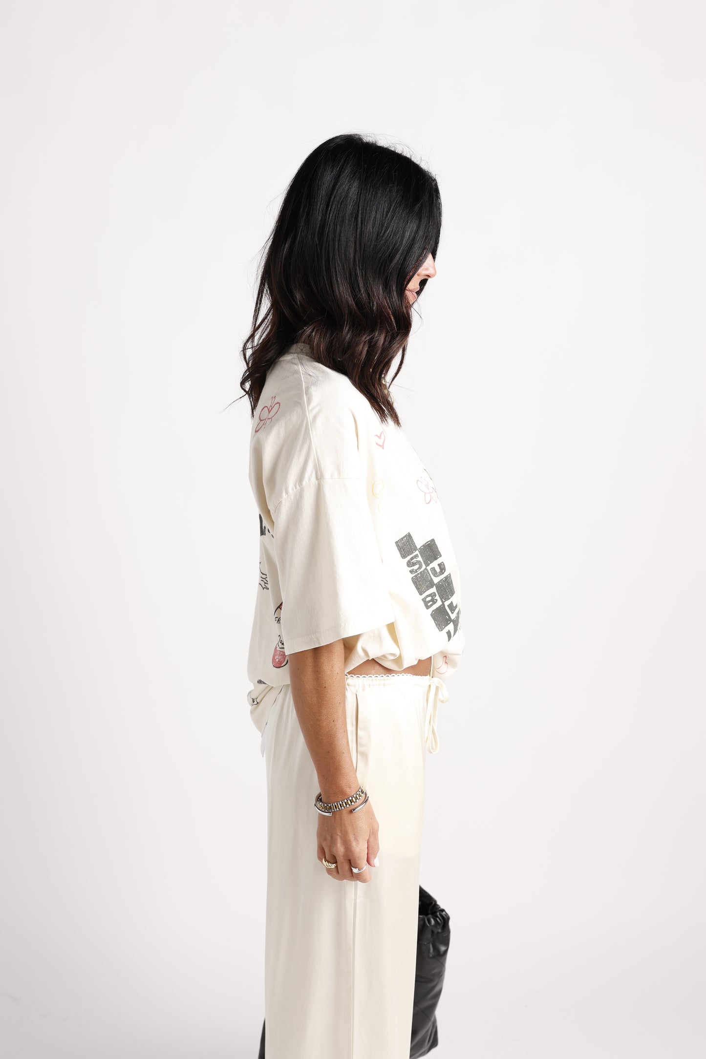 Cream oversized graphic tee with doodle prints, worn with cream wide-leg pants, side view