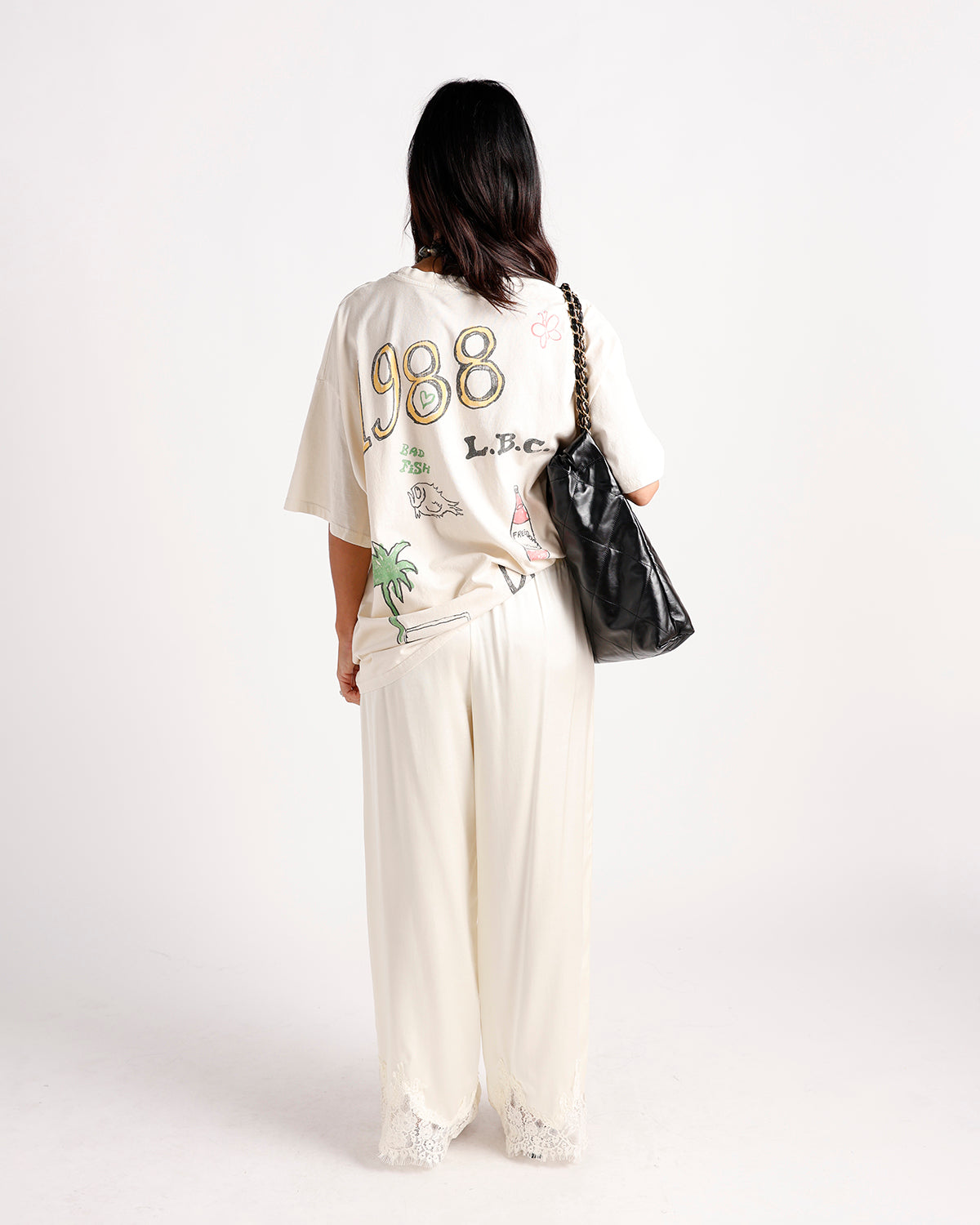 Cream wide-leg pants with white lace hem trim, styled with graphic tee
