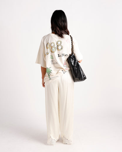 Cream wide-leg pants with white lace hem trim, styled with graphic tee