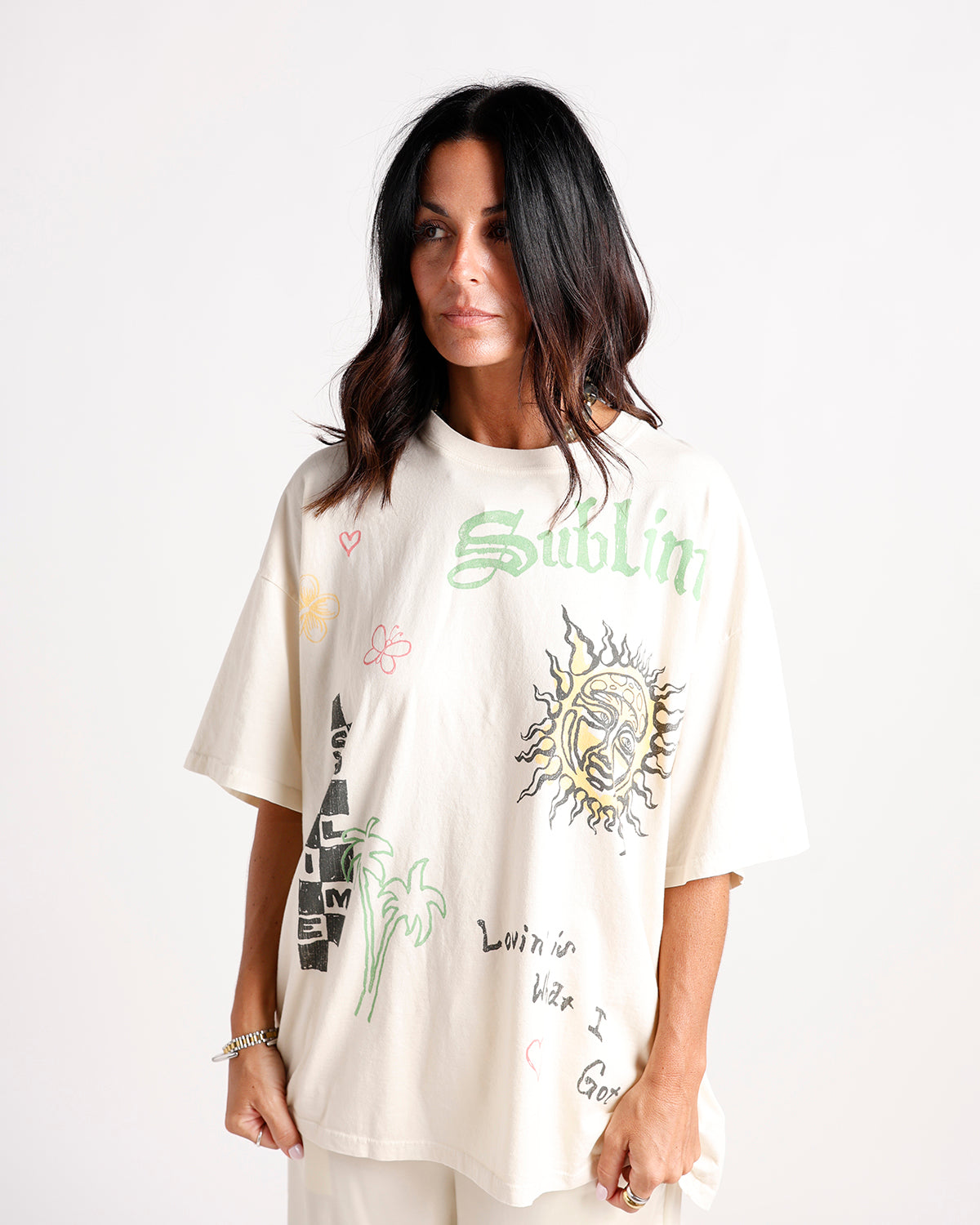 Oversized cream graphic tee with sun, palm trees, and colorful doodle prints