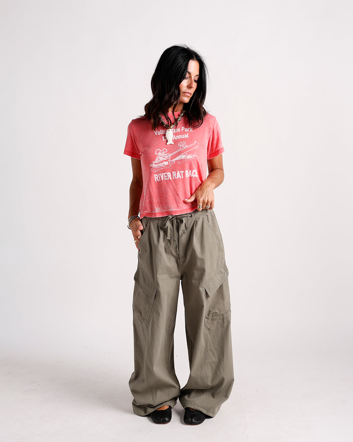 Faded coral graphic tee with River Rat Race print, worn tucked into cargo pants